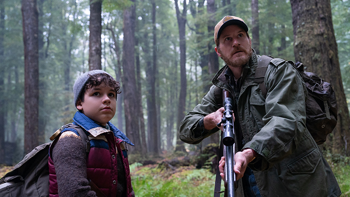 Wolf Man (2025) film still of actors Zac Chandler and Sam Jaeger holding a rifle