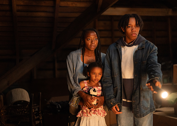 Still image of Ramona with her son and daughter all in the attic looking at the woman